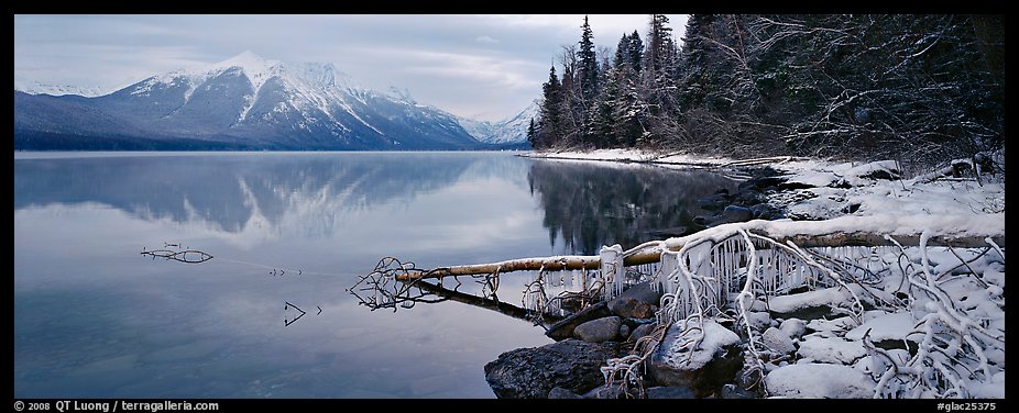 Lake, snowy shore, and mountains in winter. Glacier National Park, Montana, USA.