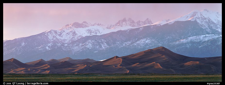Sand dunes below snowy mountain range at sunset. Great Sand Dunes National Park and Preserve, Colorado, USA.