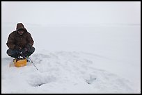 Man ice fishing on frozen Jackson Lake. Grand Teton National Park, Wyoming, USA.