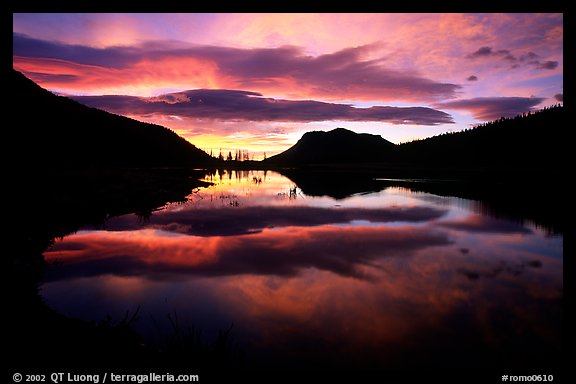 Colorful sunrise clouds reflected in a pond in Horseshoe park. Rocky Mountain National Park, Colorado, USA.