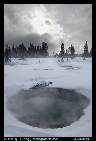 Thermal pool and dark clouds, winter. Yellowstone National Park, Wyoming, USA.