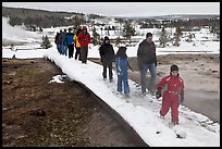 Tourists walk over snow-covered boardwalk. Yellowstone National Park, Wyoming, USA. (color)