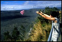 Woman throws flowers into Kilauea caldera as offering to Pele. Hawaii Volcanoes National Park, Hawaii, USA. (color)