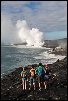 Hikers looking at molten lava and coastal volcanic steam cloud. Hawaii Volcanoes National Park, Hawaii, USA. (color)