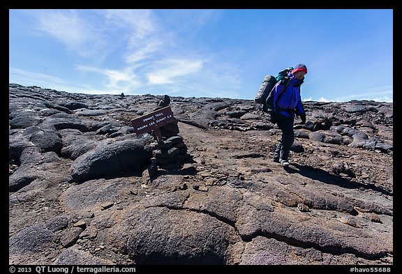 Hiker descending from Mauna Loa summit next to sign. Hawaii Volcanoes National Park (color)