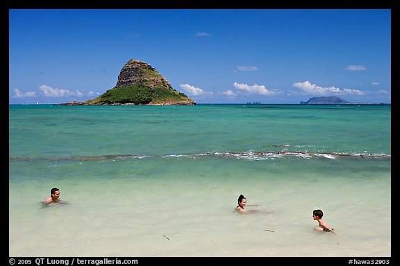 Family in the waters of Kualoa Park with Chinaman's Hat in the background. Oahu island, Hawaii, USA