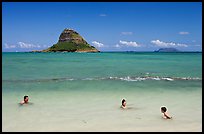 Family in the waters of Kualoa Park with Chinaman's Hat in the background. Oahu island, Hawaii, USA