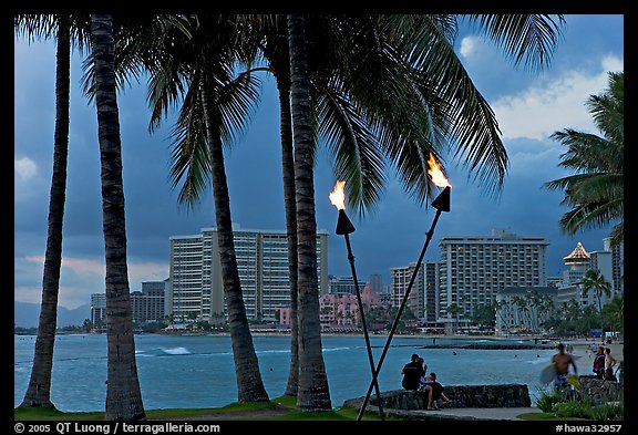 Waterfront at dusk with bare flame lamps. Waikiki, Honolulu, Oahu island, Hawaii, USA