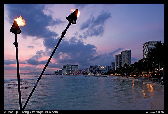 Bare flame torches and skyline at sunset. Waikiki, Honolulu, Oahu island, Hawaii, USA (color)
