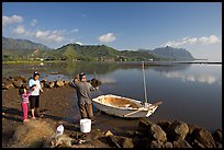 Fisherman and family pulling out net out of small baot, Kaneohe Bay, morning. Oahu island, Hawaii, USA