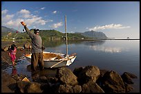 Fisherman pulling out fish out a net, with girl looking, Kaneohe Bay, morning. Oahu island, Hawaii, USA (color)
