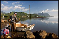Fisherman pulling out fish out a net as girllooks, Kaneohe Bay, morning. Oahu island, Hawaii, USA