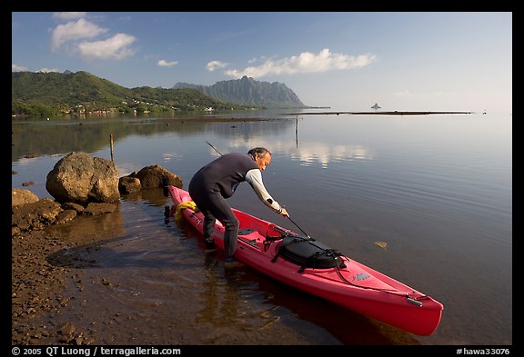 Man loading sea kayak for a fishing trip, Kaneohe Bay, morning. Oahu island, Hawaii, USA
