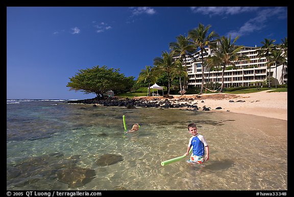 Children on Puu Poa Beach and Princeville Hotel. Kauai island, Hawaii, USA (color)