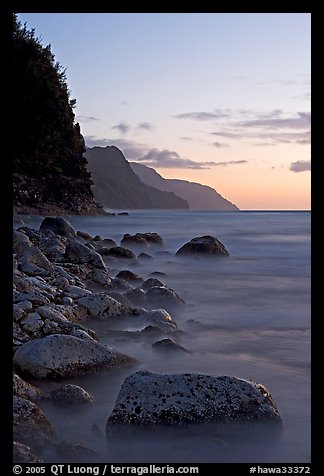 Boulders, surf, and Na Pali Coast, sunset. Kauai island, Hawaii, USA