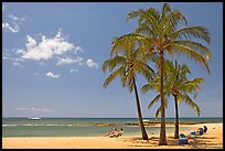 Couple on beach chair, and coconut trees,  Salt Pond Beach, mid-day. Kauai island, Hawaii, USA