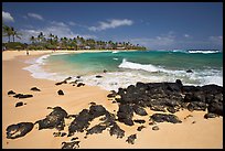 Dark rocks and Kiahuna Beach, mid-day. Kauai island, Hawaii, USA