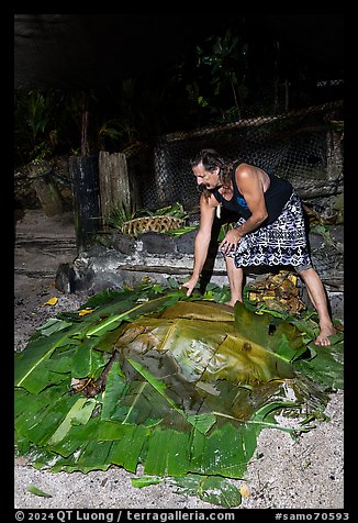 Candy Mann taking out banana leaves to uncover Umu earth oven, Tisa Barefoot Bar. Tutuila, American Samoa (color)