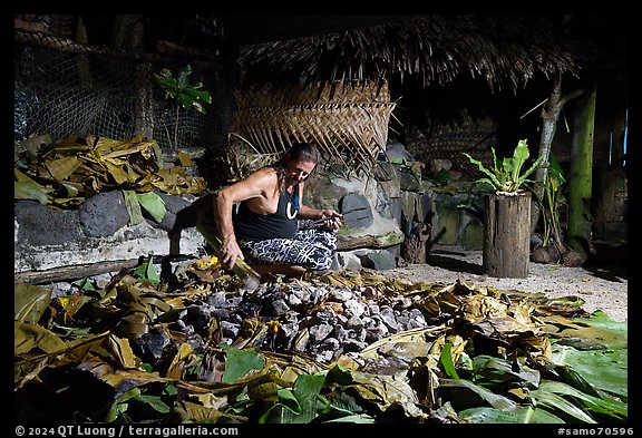 Man retrieving food cooked in Samoan traditional cooking oven powered by hot rocks. Tutuila, American Samoa (color)