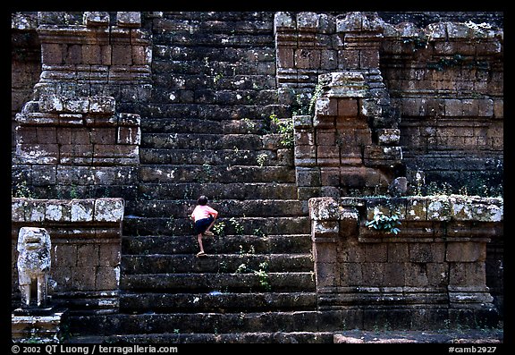 Boy climbs near-vertical staircase, Angkor Thom complex. Angkor, Cambodia (color)