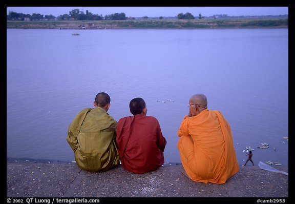 Buddhist monks sit on  banks of Tongle Sap river at dusk,  Phnom Phen. Cambodia