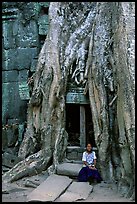 Girl sits at the base of huge bayan tree encroaching on ruins in Ta Prom. Angkor, Cambodia (color)