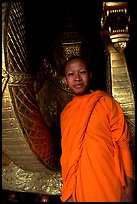 Buddhist novice monk, grinning because demonstrating ordained monks style of robe draping. Luang Prabang, Laos