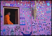 Buddhist novice monk sits at window of shrine, Wat Xieng Thong. Luang Prabang, Laos