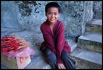 Boy sells incence sticks at the entrance of a shrine, Pak Ou. Laos