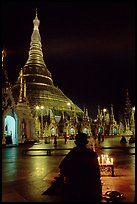 Praying at the wish-fullfilling place by night , Shwedagon Paya. Yangon, Myanmar