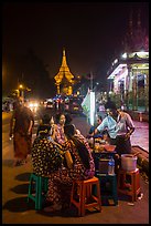 Women eating at street stall at night with Shwedagon Pagoda in background. Yangon, Myanmar ( color)