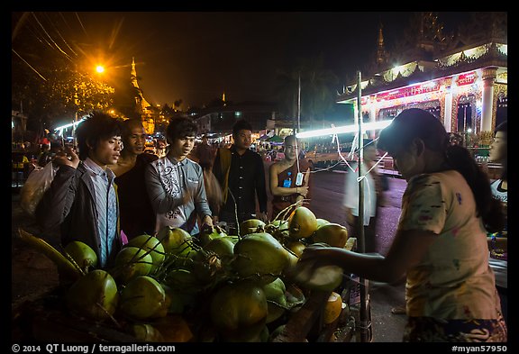 Customers waiting for coconuts to be cut on the street. Yangon, Myanmar (color)
