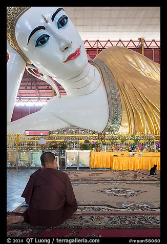 Monk praying in front of reclining Buddha statue, Kyaukhtatgyi Pagoda. Yangon, Myanmar (color)