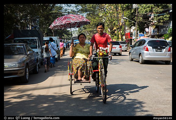 Woman holding unbrella against sun while riding Trishaw. Yangon, Myanmar (color)
