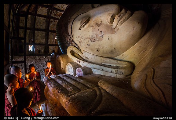 Young monks with candles worship Shin Bin Thal Yaung reclining Budddha. Bagan, Myanmar (color)