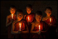 Young buddhist monks holding candles with eyes closed. Bagan, Myanmar ( color)