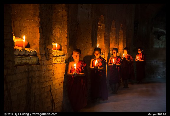Buddhist novices in temple illuminated with candles. Bagan, Myanmar
