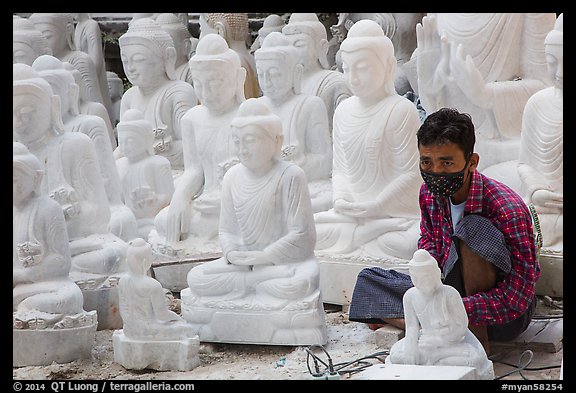 Man working amongst many  buddha statues on Marble street workshop. Mandalay, Myanmar (color)