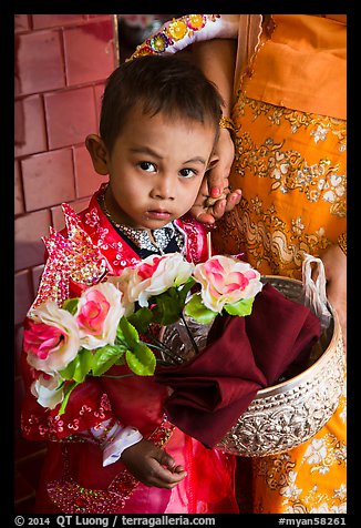 Child carrying offering bowl and flowers for novitiation ceremony, Mahamuni Pagoda. Mandalay, Myanmar (color)