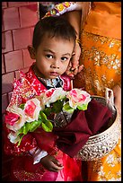 Child carrying offering bowl and flowers for novitiation ceremony, Mahamuni Pagoda. Mandalay, Myanmar ( color)
