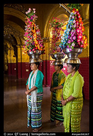 Women carry elaborate flower offerings on their head, Mahamuni Pagoda. Mandalay, Myanmar (color)