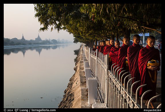 Monks walking in line in alm bowls near Mandalay Fort moat. Mandalay, Myanmar (color)