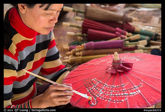 Woman painting the red umbrellas carried by the monks. Pindaya, Myanmar (color)