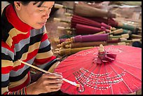 Woman painting the red umbrellas carried by the monks. Pindaya, Myanmar ( color)