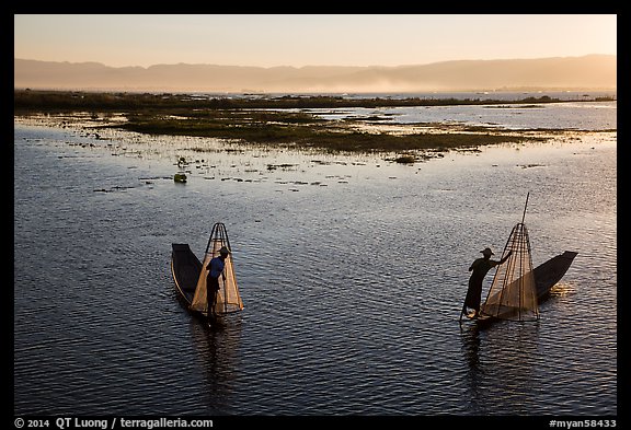 Intha fishermen row with backlit conical nets. Inle Lake, Myanmar