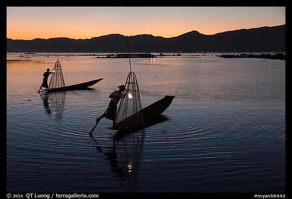 Leg-rowing Intha fishermen with lanterns at dusk. Inle Lake, Myanmar