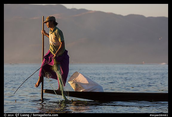 Fisherman pulling up net while leg-rowing. Inle Lake, Myanmar