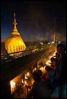 Pilgrims light up candles behind the Golden Rock at dusk. Kyaiktiyo, Myanmar ( color)