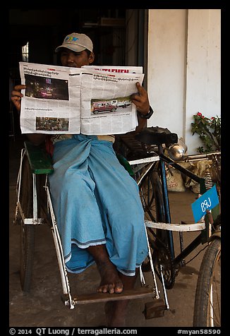 Cyclo driver reading newspaper with picture of QT Luong tour group. Bago, Myanmar (color)