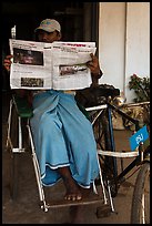 Cyclo driver reading newspaper with picture of QT Luong tour group. Bago, Myanmar ( color)
